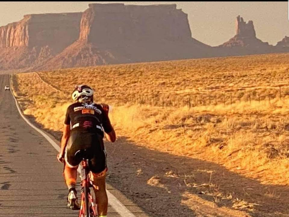 A cyclist riding through a dramatic landscape at first light